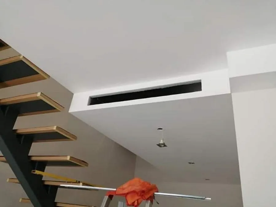 Grelha linear de duto no forro ao lado de uma escada