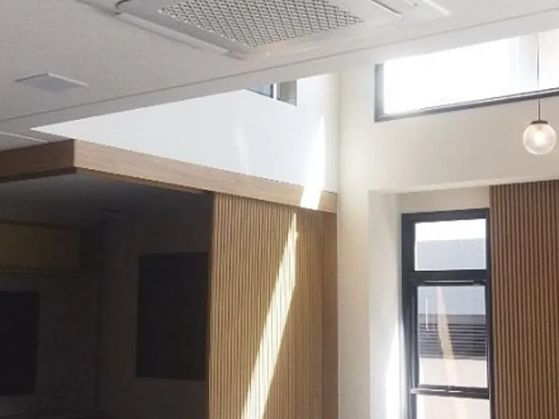 Sala de pé direito alto com ar condicionado cassete no teto
